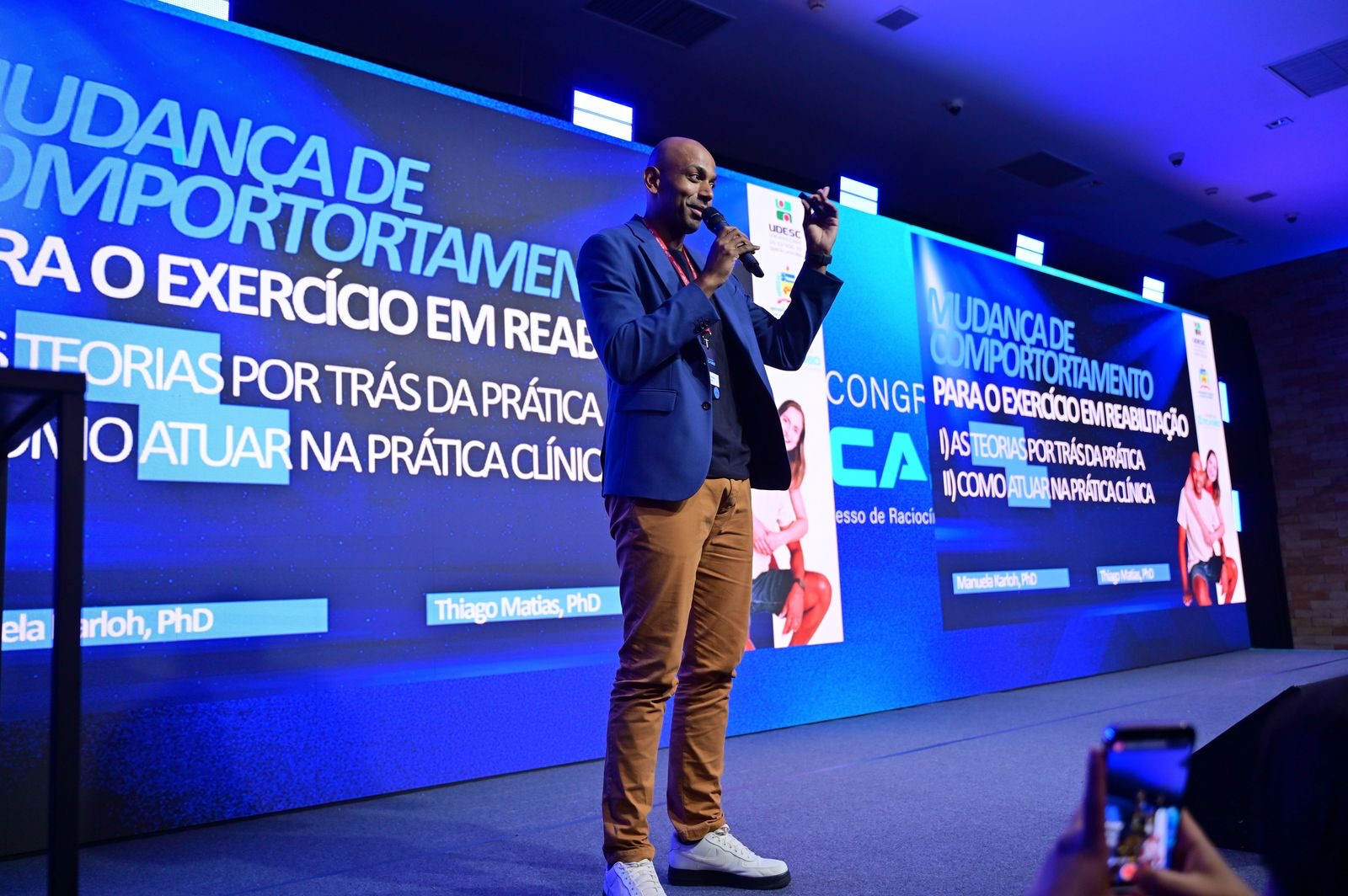 Thiago Matias no palco, durante a palestra Mudança de Comportamento para o Exercício em Reabilitação